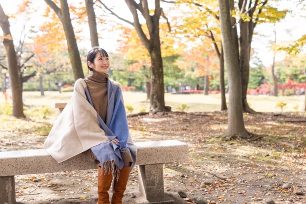 秋の公園でベンチに座る女性
